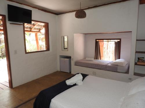 a bedroom with two beds and a tv on the wall at Pousada Santa Aldeia in Barra Grande