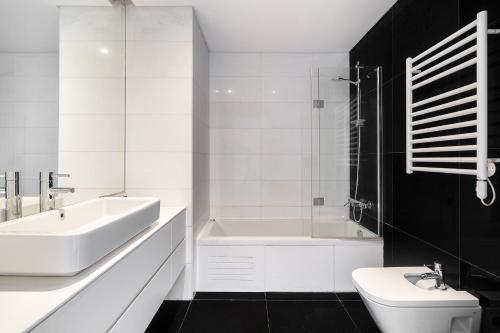 a white bathroom with a sink and a tub and a toilet at WHome Urban Retreat w/Parking, Elevator & AC by Benfica Stadium in Lisbon