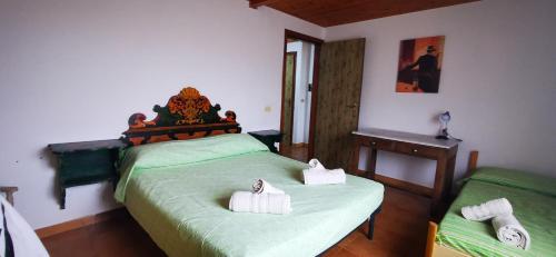 Casa vacanze CALU' في سيتاديلا ديل كابو: غرفة نوم بسرير اخضر عليها منشفتين بيض