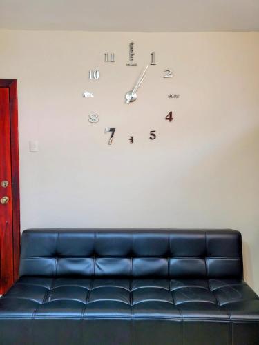 a clock on a white wall with a blue couch at NCG Suite in Guayaquil