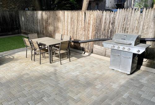 Un patio con parrilla y mesa y sillas. en Lincoln Park Apartment with Backyard!, en Chicago