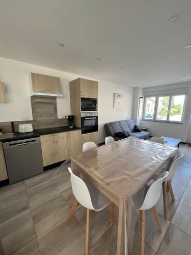 a kitchen and living room with a wooden table and chairs at Maison proche Le Pal in Neuilly-le-Réal