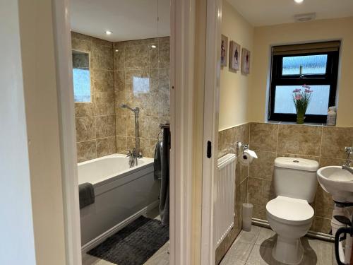 a bathroom with a tub and a toilet and a sink at Huntspill Cottage in Lincolnshire