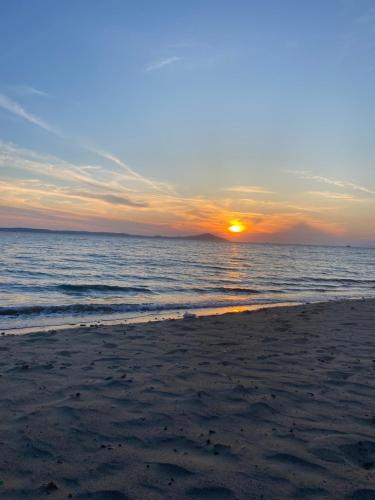 a sunset on a beach with the ocean at Geyikli Ada Apart Otel in Geyikli