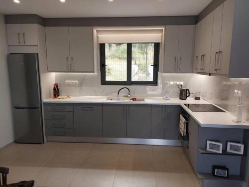 a kitchen with white cabinets and a sink and a window at Iliovasilema in Mírton