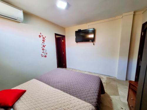 um quarto com uma cama e uma televisão na parede em NCG Suite em Guayaquil