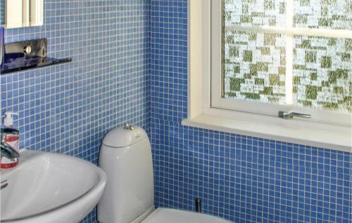 a blue tiled bathroom with a toilet and a sink at Amazing Home In Drbak With Kitchen in Drøbak