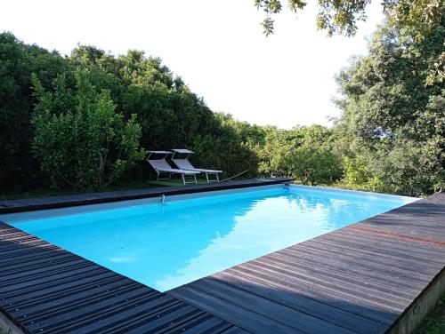 - une piscine avec deux chaises assises sur une terrasse en bois dans l'établissement Sardinia Ovest 2, à Putzu Idu