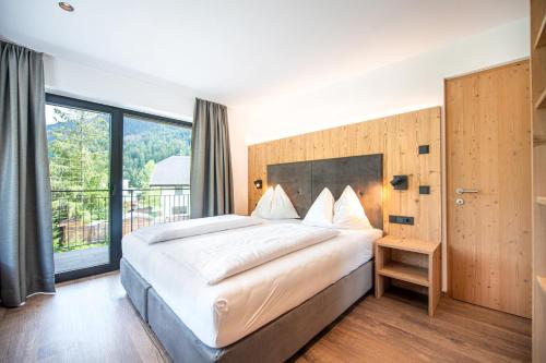 een slaapkamer met een groot bed en een groot raam bij Apartments LaBar in Ortisei