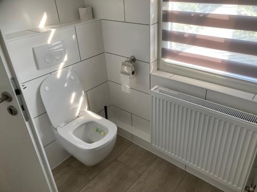 a white bathroom with a toilet and a window at P7 gemütliche Ferienwohnung 
