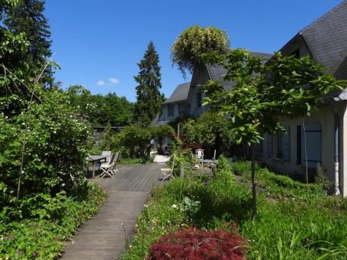 a garden with a wooden walkway next to a house at Le jardin de Saint Jean in Saint-Jean-aux-Bois