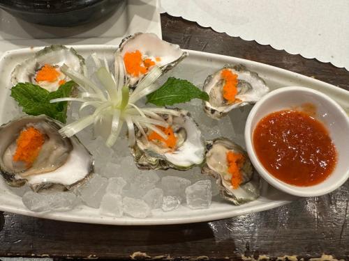 a plate of oysters with a bowl of dipping sauce at Room in Vietnam 1 in Ben Tre
