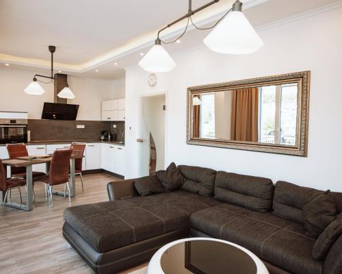 een woonkamer met een bruine bank en een keuken bij Ferienhaus Moselpromenade in Zell an der Mosel