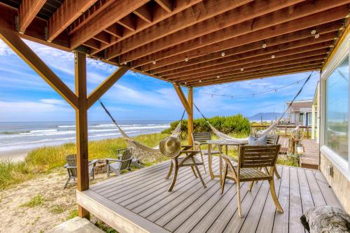 a porch with a hammock and chairs on the beach at Salty Shore in Rockaway Beach