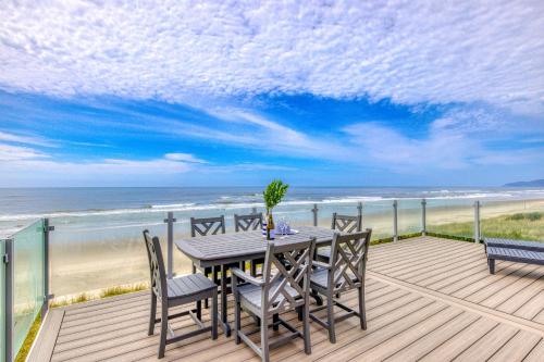 a table and chairs on a deck with the beach at Salty Shore in Rockaway Beach