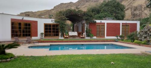 a house with a swimming pool in the yard at Las buganvilias in Pachacamac