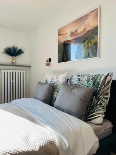 a bed with pillows and a painting on the wall at Mare e Monti Apartments in Katowice