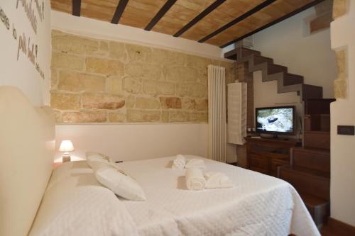 Schlafzimmer mit einem Bett mit weißer Bettwäsche und einem TV in der Unterkunft BIBI'S HOUSE in Terrasini