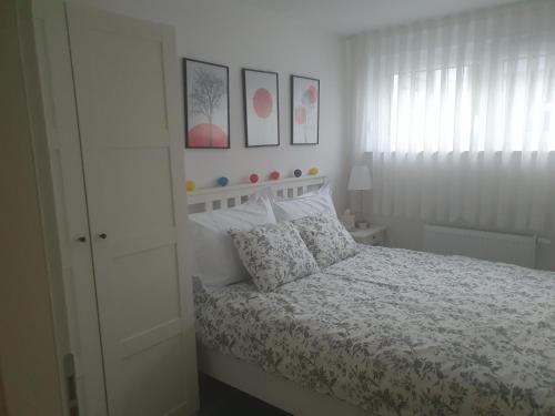 a white bedroom with a bed and some pictures on the wall at Cosy 35m2 appartment in Zagreb