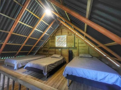 two beds in a attic room with a roof at Espectacular Cabaña Loft en Guatape - Jacuzzi in El Peñol