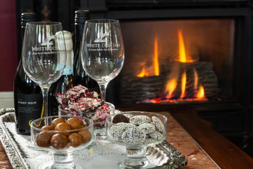 a table with two wine glasses and a fireplace at White Doe Inn Bed & Breakfast in Manteo
