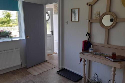 a hallway with a door and a mirror and a window at Emma's Cottage in Brookeborough