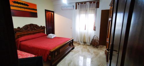 um quarto com uma cama vermelha e uma janela em B&B Calù em Cittadella del Capo