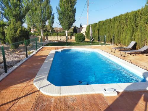 a swimming pool with a wooden deck and blue water at Casa rural cascales in Cervera del Llano