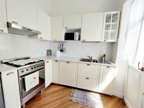 una cocina blanca con armarios blancos y fregadero en Viaemilia Alessandria, en Alessandria