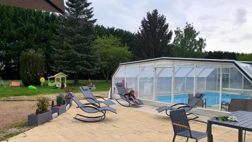 a group of chairs sitting on a patio next to a greenhouse at Bois de Crâne in Landes-le-Gaulois