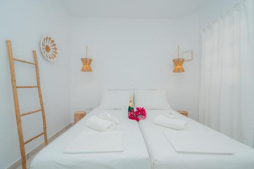 um quarto branco com uma cama branca com flores em Nostos Sifnos em Apollonia