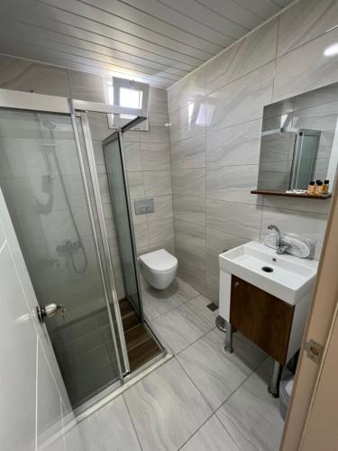 een badkamer met een douche, een wastafel en een toilet bij Esmeralda Butik Hotel in Kızılot