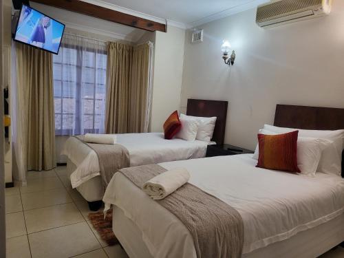 a hotel room with two beds with a tv on the wall at Generosa of the North in Durban