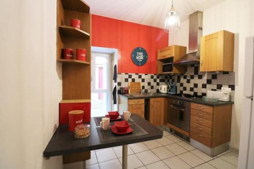 une cuisine avec des murs rouges et un comptoir noir dans l'établissement LE MOULIN A VENT maison plein centre de SARLAT, à Sarlat-la-Canéda