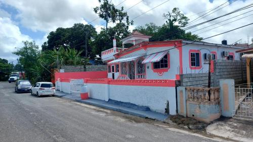 a red and white house on the side of a street at Charming 1-Bedroom House in St Thomas Jamaica in Belfast