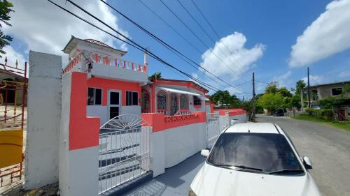 a white car parked next to a red and white building at Charming 1-Bedroom House in St Thomas Jamaica in Belfast