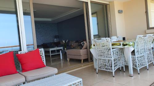 uma sala de estar com cadeiras brancas e uma mesa e uma sala de jantar em Prestigia bouknadel em Sidi Bouqnadel