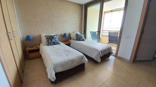 a hotel room with two beds and a balcony at Prestigia bouknadel in Sidi Bouqnadel