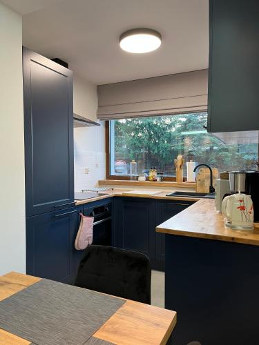 a kitchen with blue cabinets and a large window at Modern Village in Nowinka