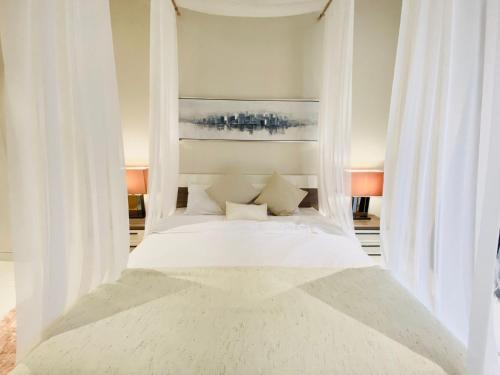 - un lit blanc avec des rideaux blancs dans une chambre dans l'établissement Casa Salalah, cozy 2-storey townhouse in Hawana Salalah with free Wi-Fi, à Salalah