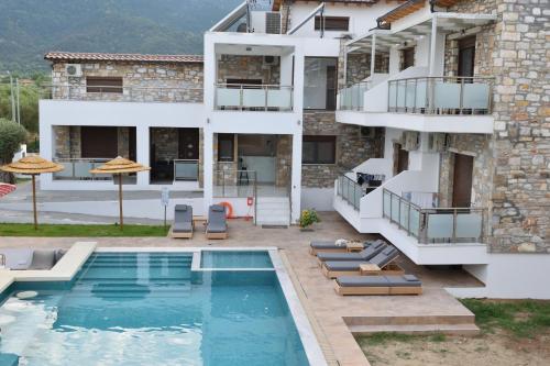 a villa with a swimming pool in front of a building at Dioscuri Deluxe Apartments in Chrysi Ammoudia