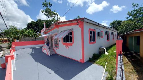 a red and white building with a person standing outside at Lovely 2 Bedroom House in St Thomas Jamaica in Belfast