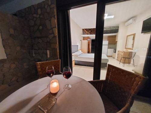 a table with two glasses of wine and a room at Prego Living Apartments in Vathí