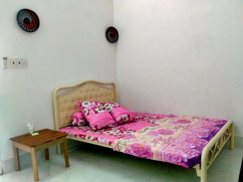 een bed met roze kussens en een tafel in een kamer bij Room in Vietnam 1 in Ben Tre