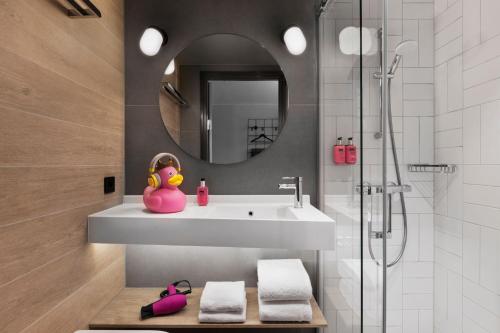 a bathroom with a sink and a pink duck sitting on a bench at Moxy Bergen in Bergen