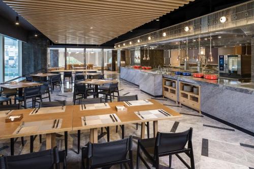 a restaurant with wooden tables and chairs and a kitchen at Sheraton Nanjing Kingsley Hotel & Towers in Nanjing