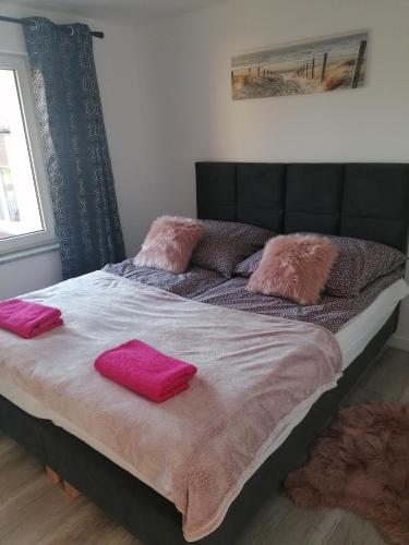 ein großes Bett mit zwei rosa Kissen darauf in der Unterkunft Apartament Kasztanowa 2 in Mosty
