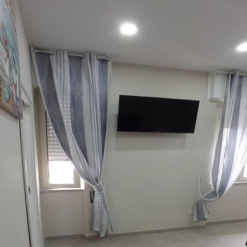 a room with curtains and a tv and a window at Casa vacanze Via Treglia in Scauri