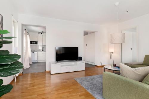 a living room with a flat screen tv and a couch at Guestly Homes - 3BR Modern Apartment in Piteå