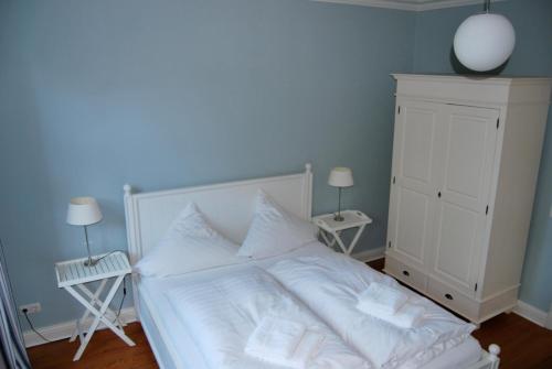 a bedroom with a white bed with two lamps and a dresser at Villa Baltica - Garten-Appartement in Schönberg in Holstein